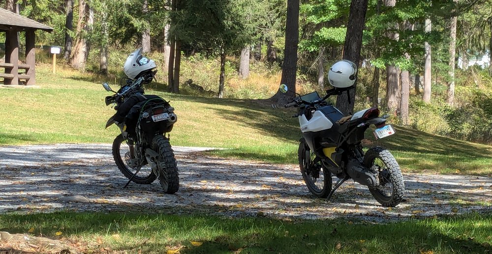 the two motorcycles parked at a picnic area in the woods