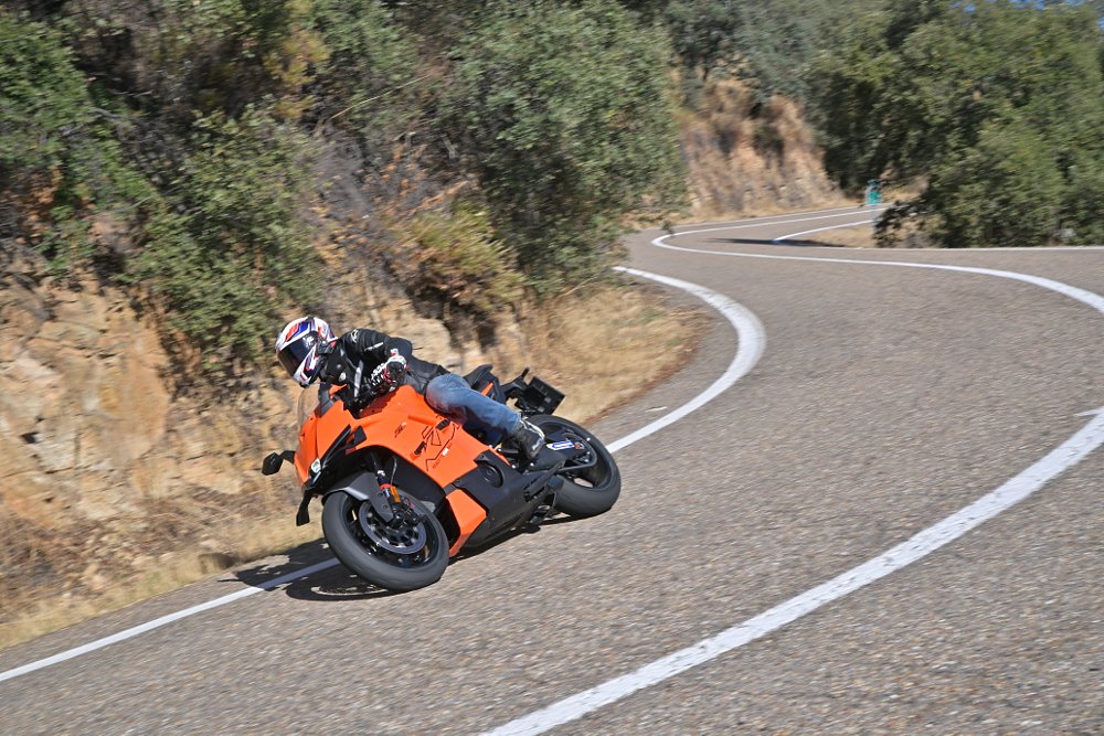 2026 KTM 990 RC R riding on a twisty road through a forest.