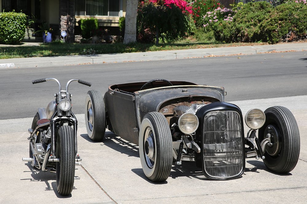 the custom motorcycle parked next to a custom hot-rod open car