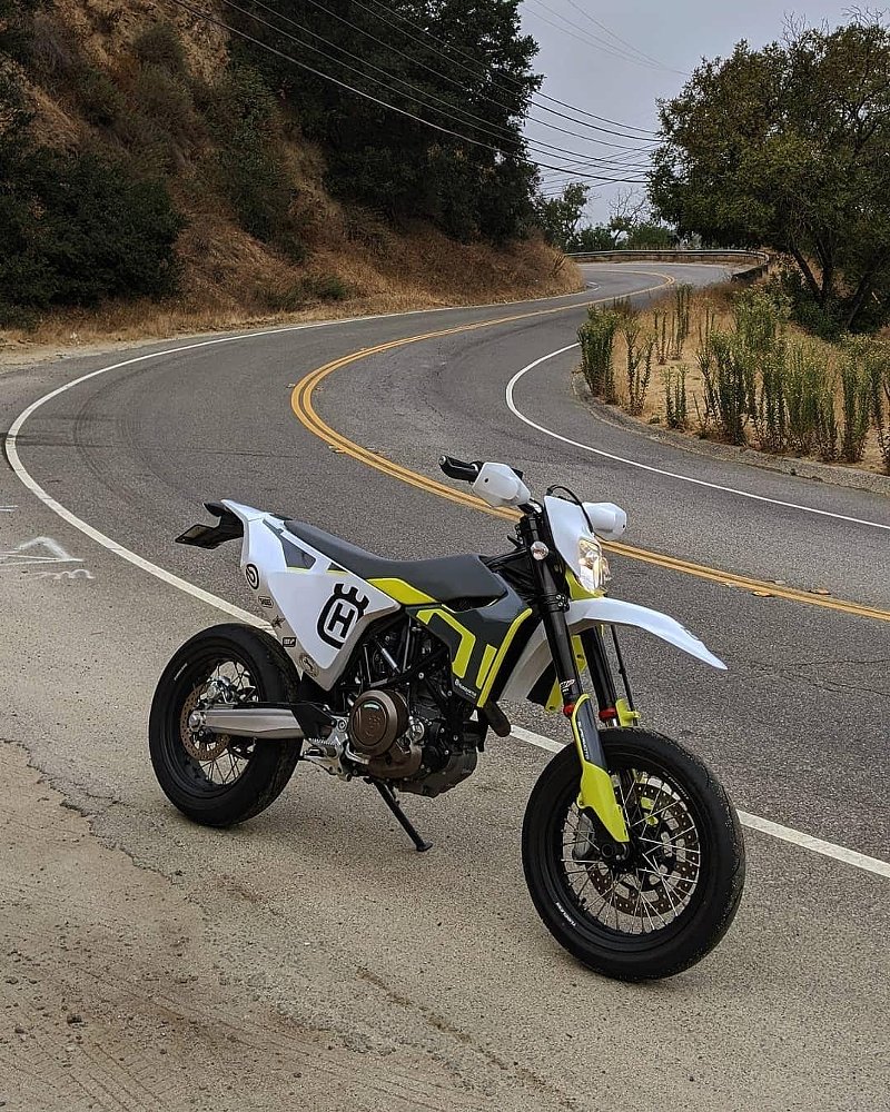 white Husqvarna 701 supermoto parked on a curving canyon road