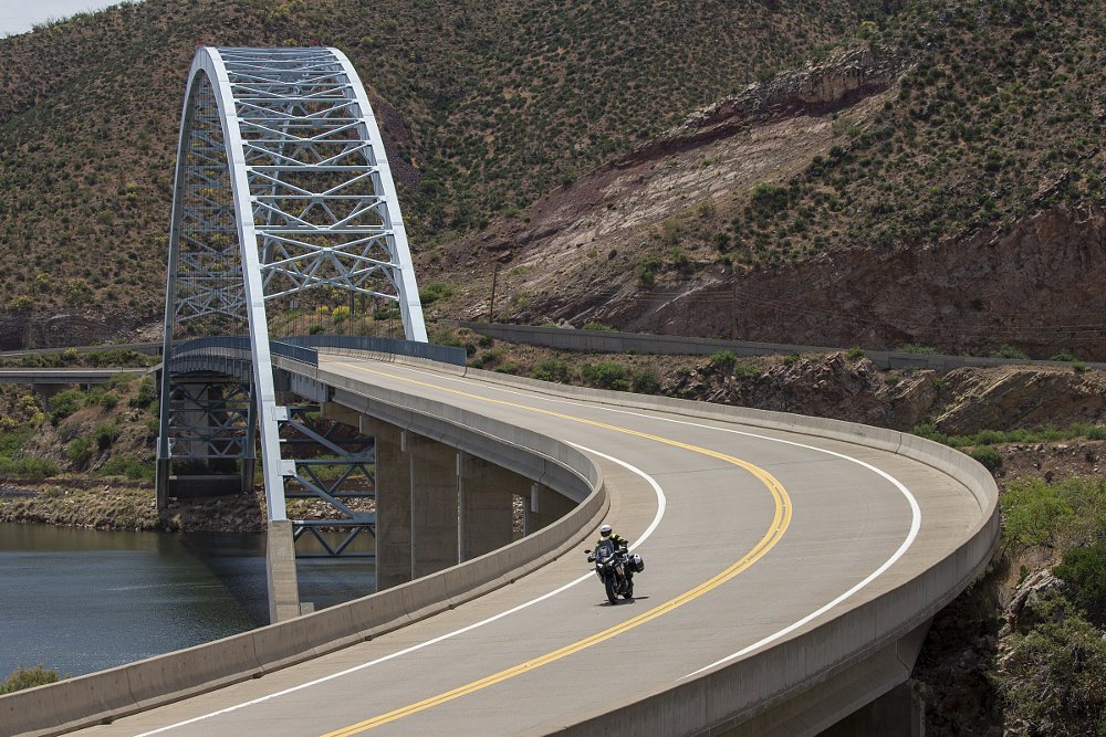 long distance photo of a motorcycle crossing a bridge on a road in the southwestern U.S.