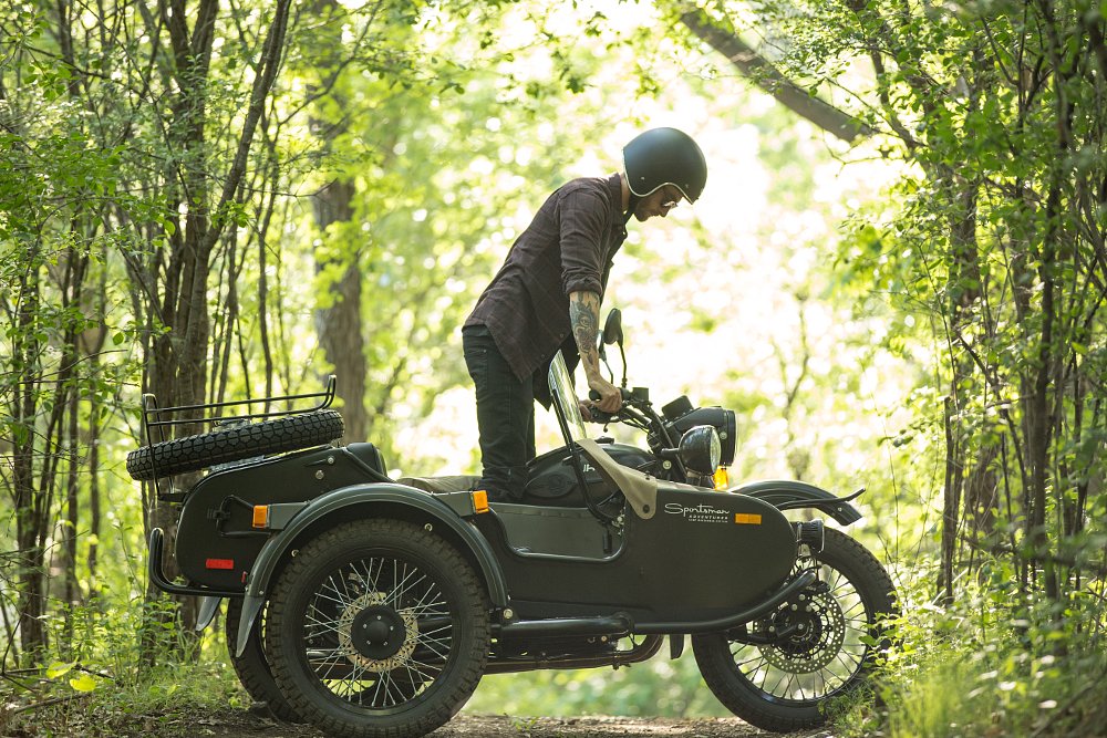 rider wearing a retro style helmet in the woods on a Ural with sidecar