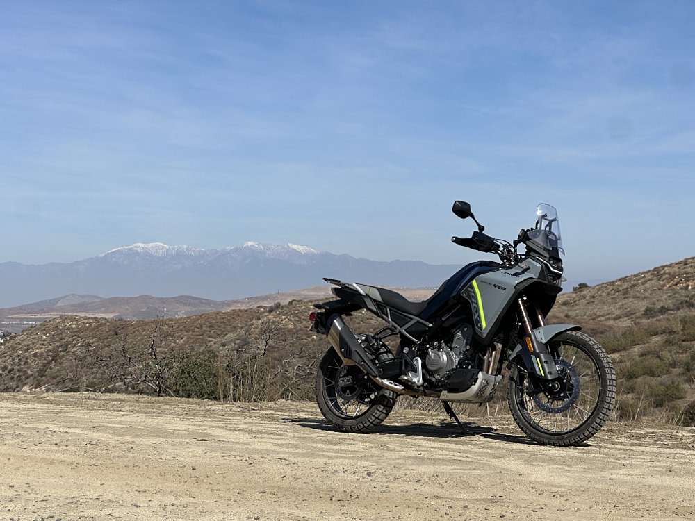 2025 CFMOTO Ibex 450 parked with snow-capped mountains in the background.