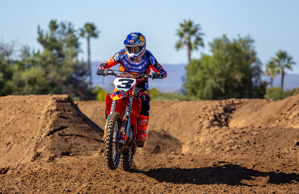 Tomac on the orange KTM on a practice track with palm trees and the ocean in the distant background