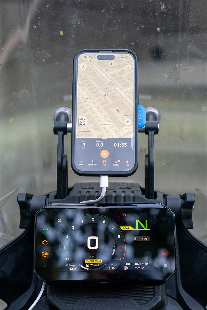 A close-up of the Ibex 450's TFT dash with an iPhone 14 mounted above it.