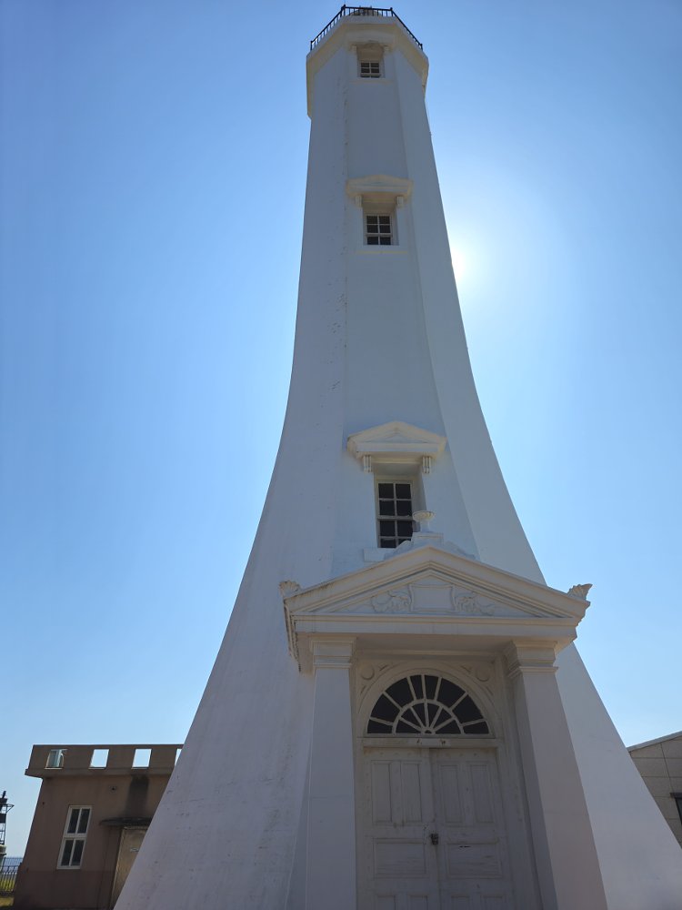 white lighthouse rising against a clear blue sky