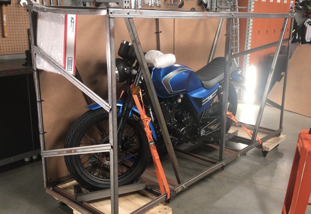 a blue CSC motorcycle inside a metal frame for shipping