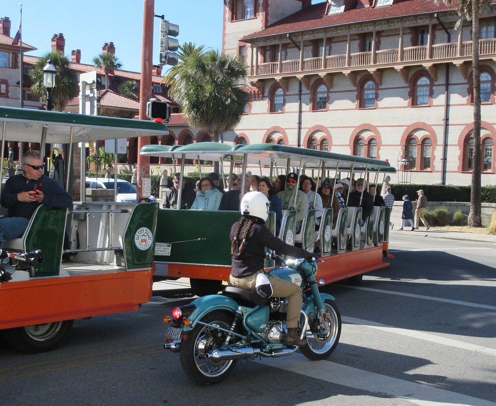 woman rider on a teal Classic 650 beside an open-air tour bus in St. Augustine