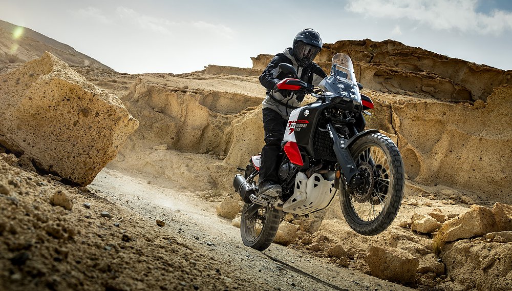 A Ténéré 700 World Raid rider hoists a wheelie on a desert trail.