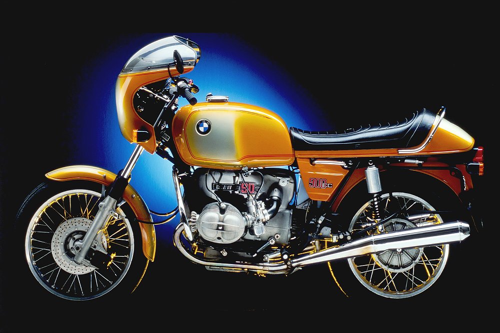 The 1976 BMW R90S shot against a blue-lit black background.