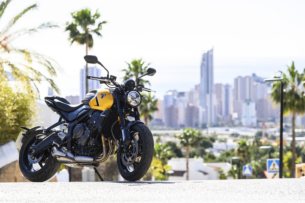 Yellow Trident 660 parked at an overlook with a cityscape in the distance