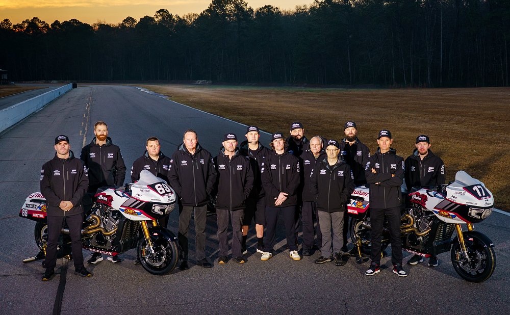 the entire team lined up with the three King of the Baggers race bikes at the track at sunset