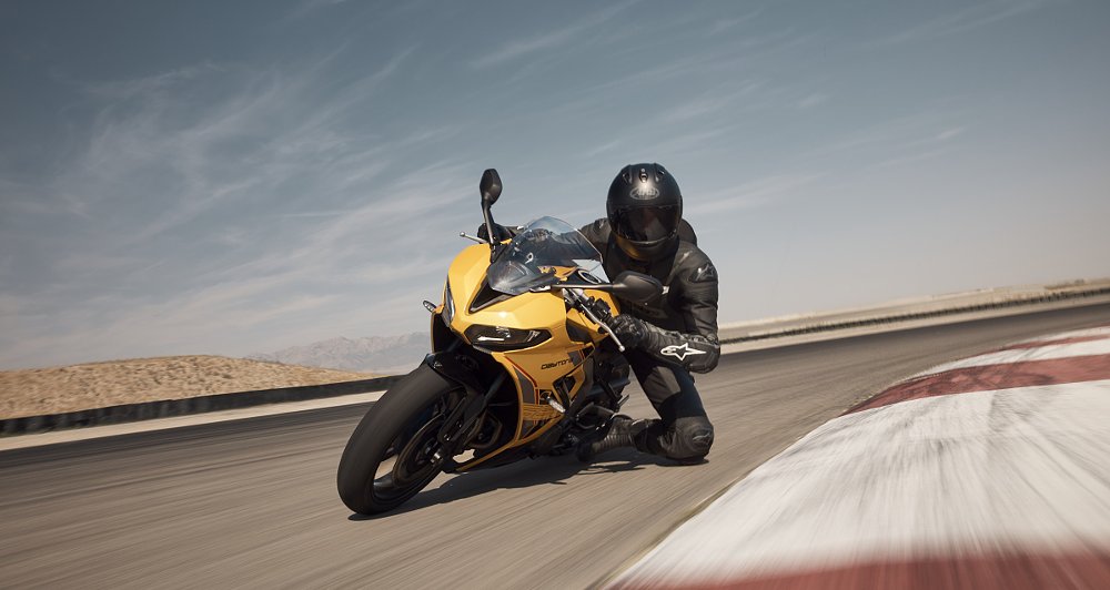 rider in black leathers on a yellow Daytona, knee down in a corner on the track