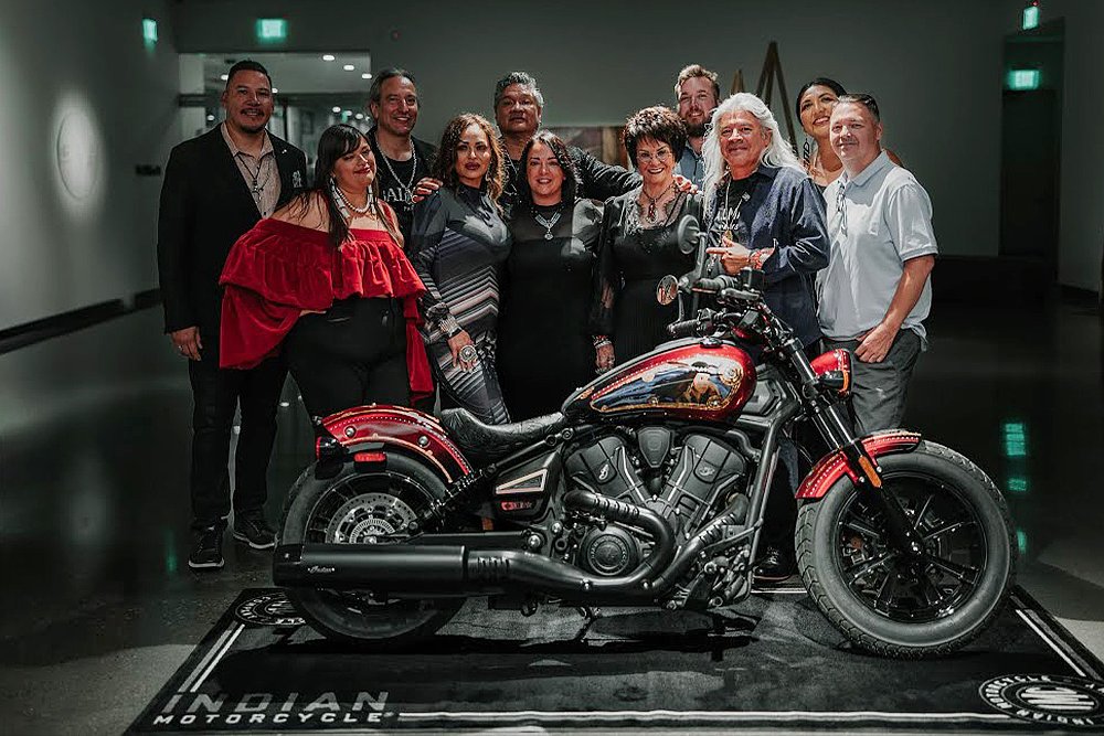 A group of Native American artists stand before a customized Indian Scout.