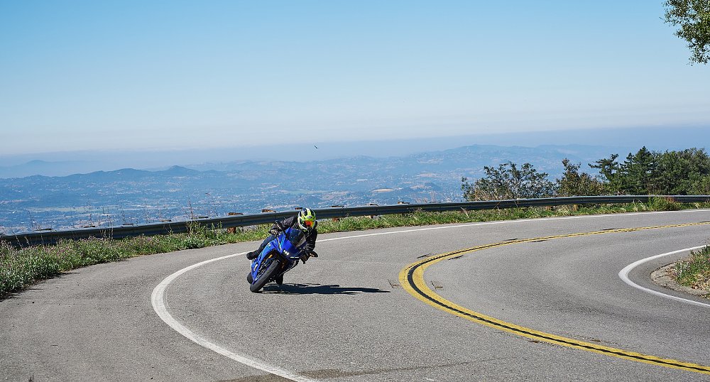 rider rounding a curve on a blue R7 atop a mountain