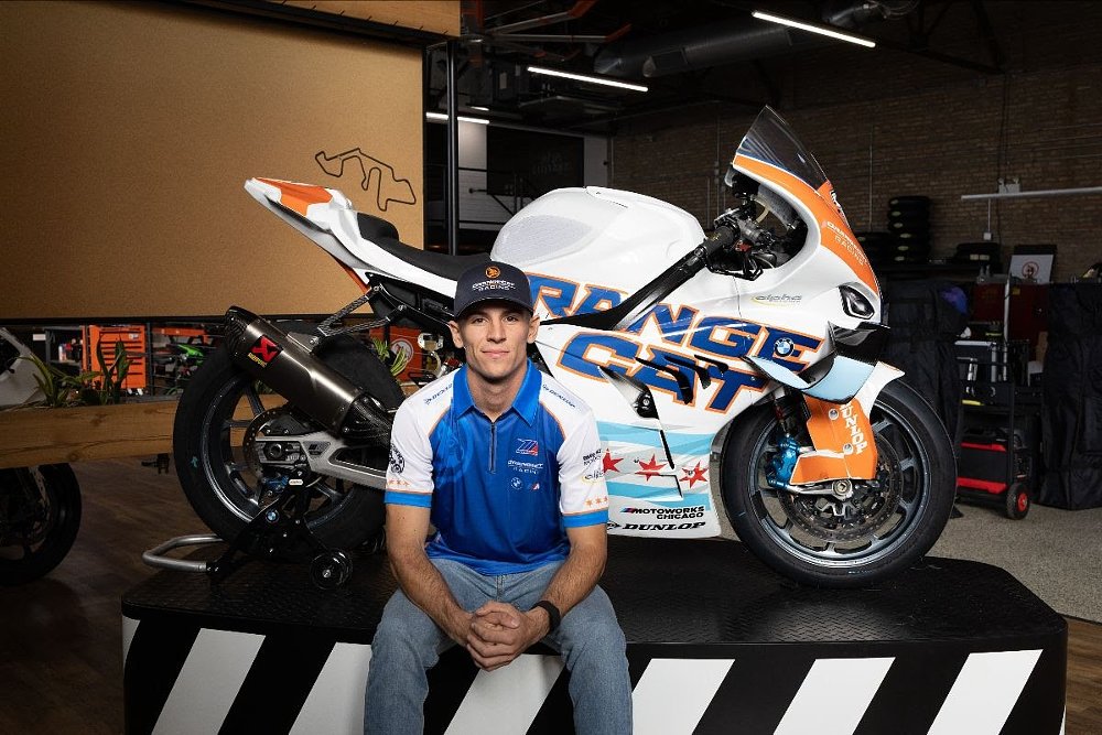 Sean Dylan Kelly posing in front of his white and orange OrangeCat Racing BMW