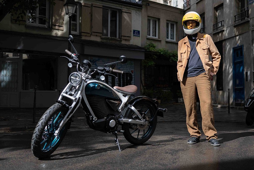 A rider stand beside the Flying Flea C6 electric motorcycle.
