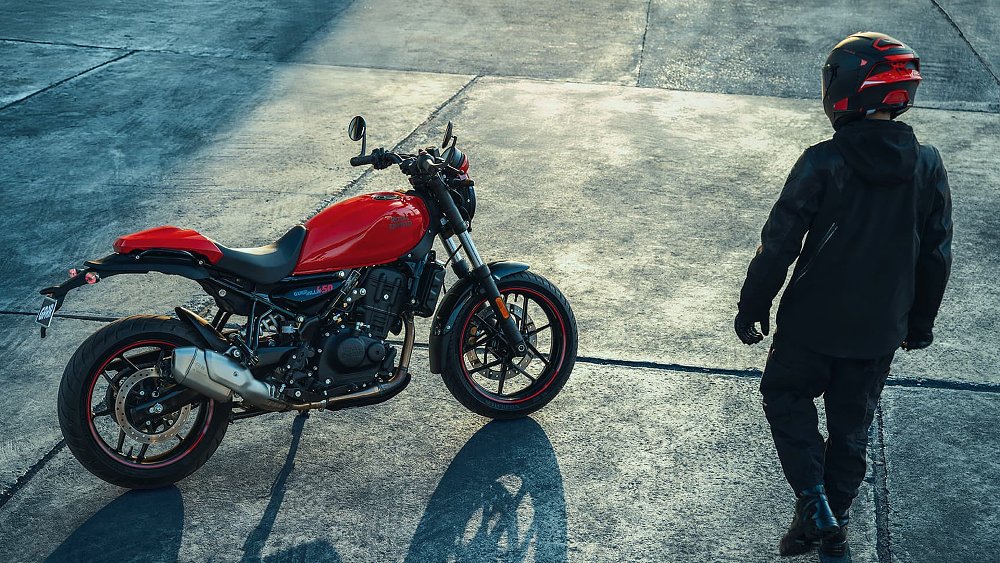 A rider approaches the Guerrilla 450 Apex parked in an urban area.