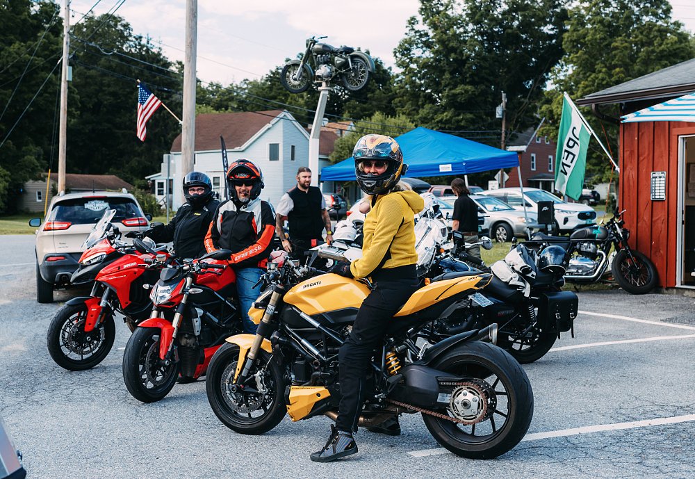 three riders on Ducatis stopped in front of a country motorcycle shop