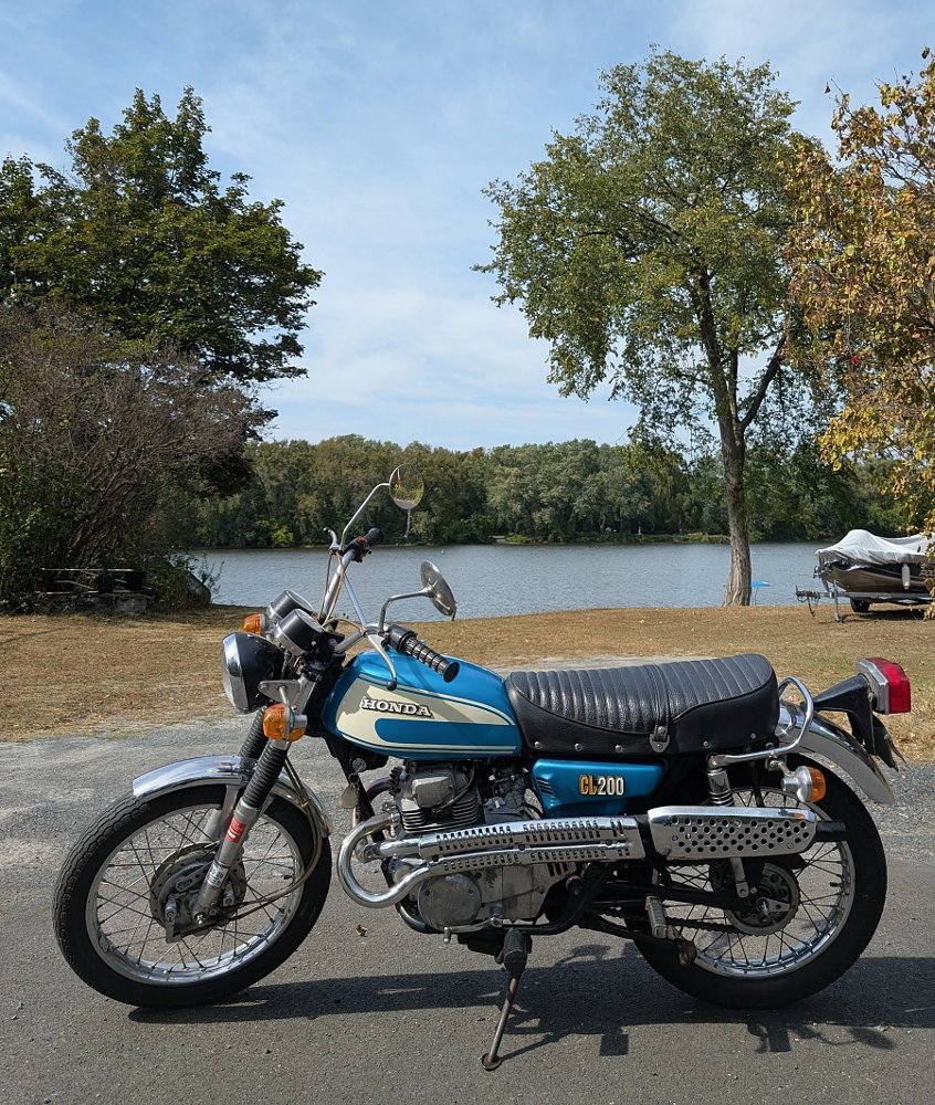 little blue vintage Honda parked in front of a river