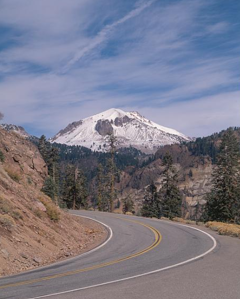 green Kawasaki sport motorcycle parked along a curve with a snow-topped mountain in the background