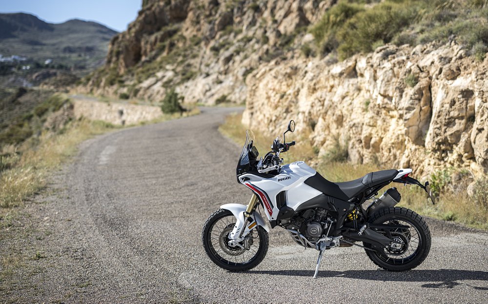 The white DesertX parked on a dirt road in the mountains, left side view