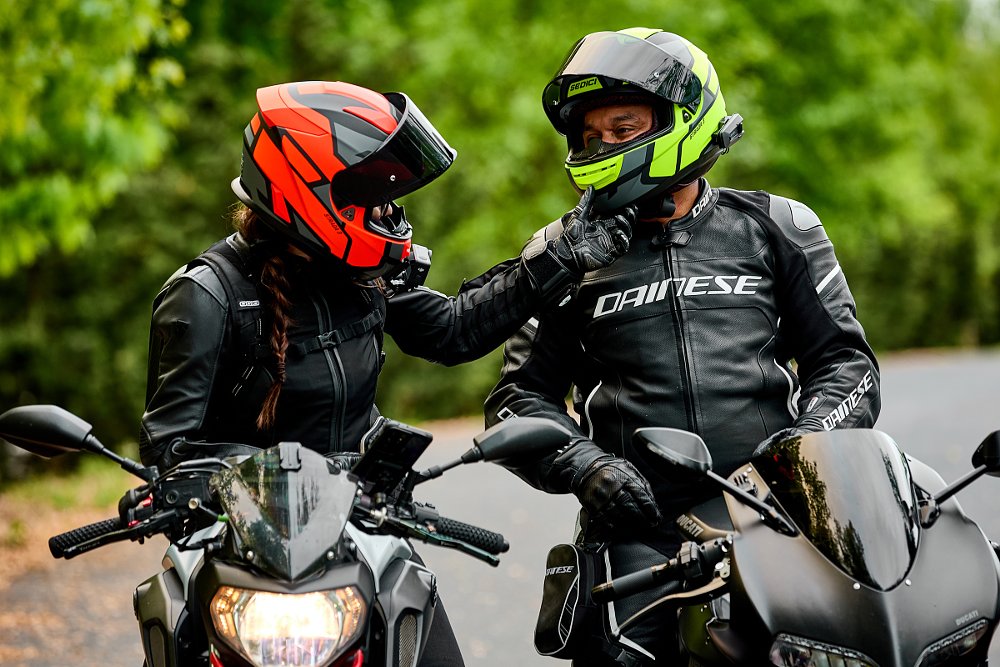 two riders, a woman and a man, on sport naked bikes talking at a stop