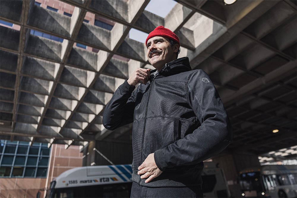 A rider on an urban street zips up the zipper on his mesh hoody.