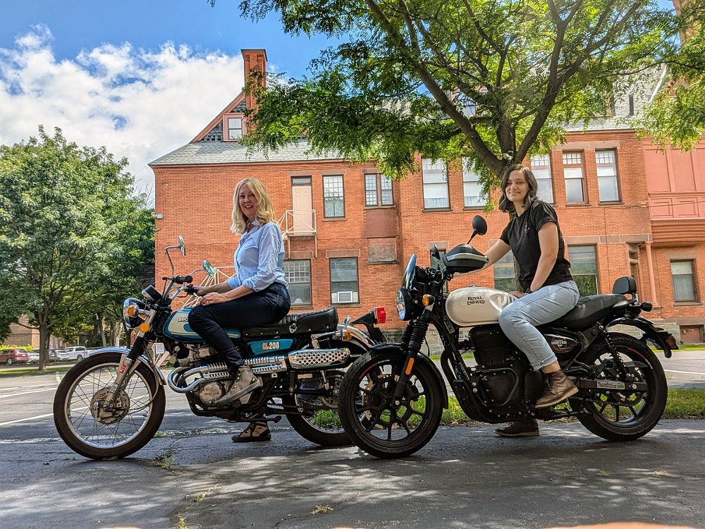 two women riders on small motorcycles, ready to practice