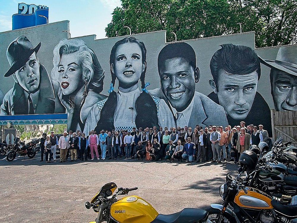 group of riders in the DGR under a large mural