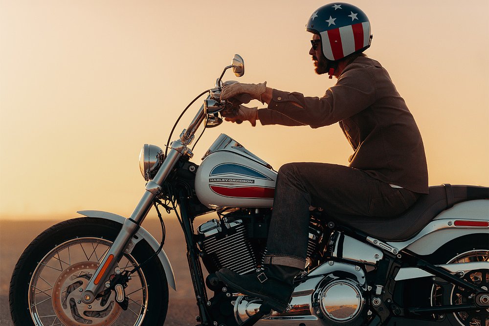A rider poses on the 2026 Super Glide with a beach in the background.