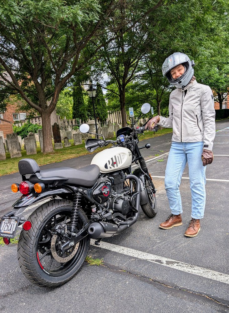 woman rider standing beside her white Royal Enfield Hunter 350