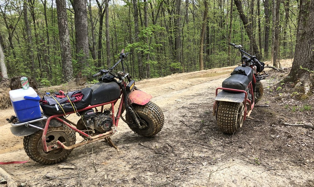 two muddy minibikes parked by the trail