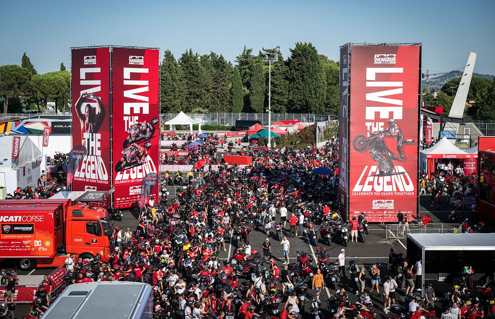aerial view of rows of Ducati motorcycles parked by a tower with a huge Ducati banner