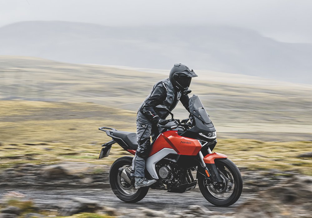 rider on the orange Norton Atlas standing up while riding off-road
