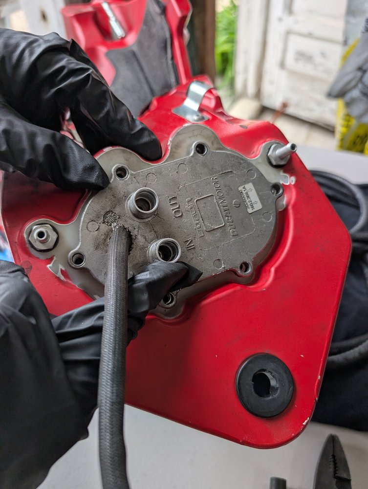 gloved hand holding the Streetfighter's fuel pump with the hose clearly detached