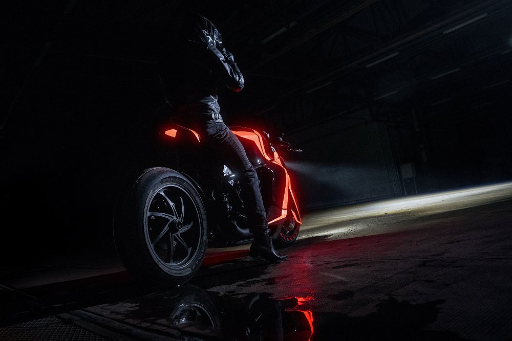 rear angle view in the dark of a rider on the bike with orange-red panels glowing