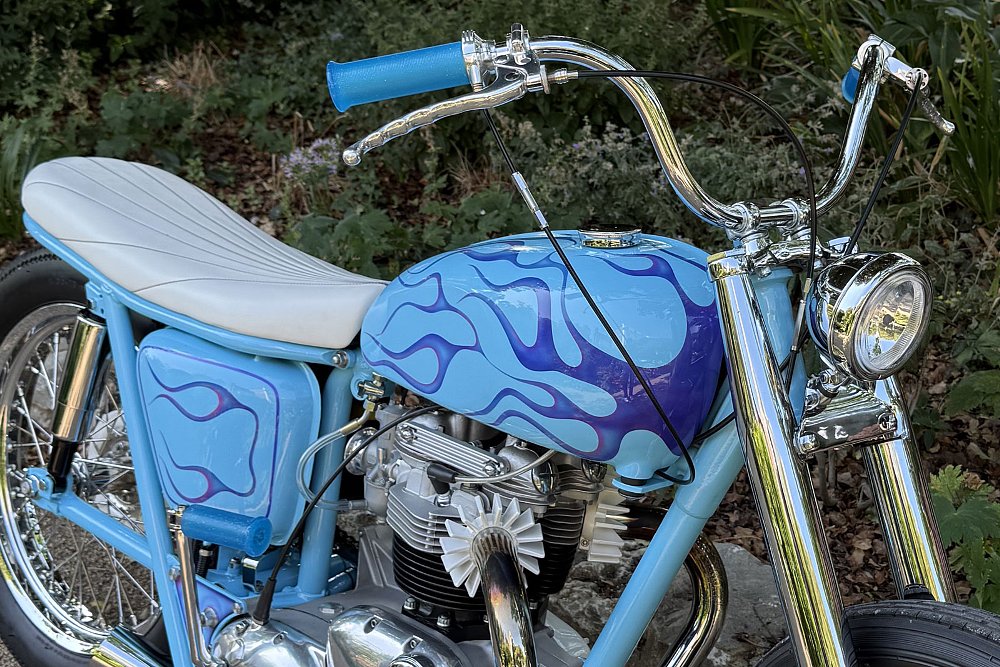 front three-quarters view showing the chrome handlebar and blue flame paint on the tank