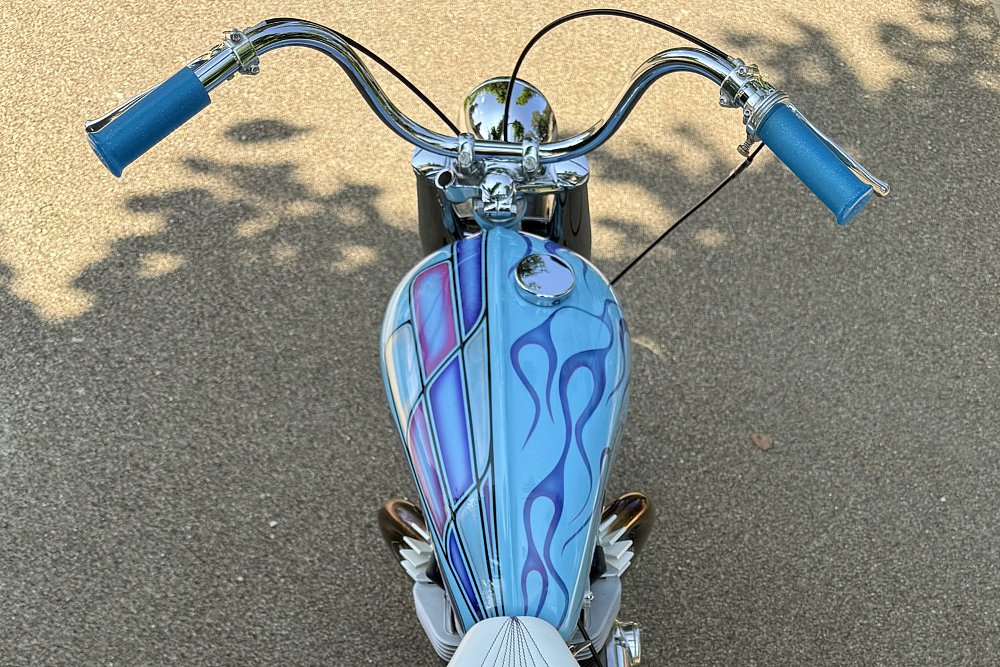 cockpit view of the chromed handlebar and blue tank with asymmetrical paint