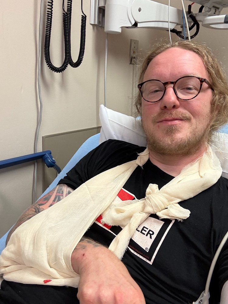 the writer in a hospital bed, arm in a sling