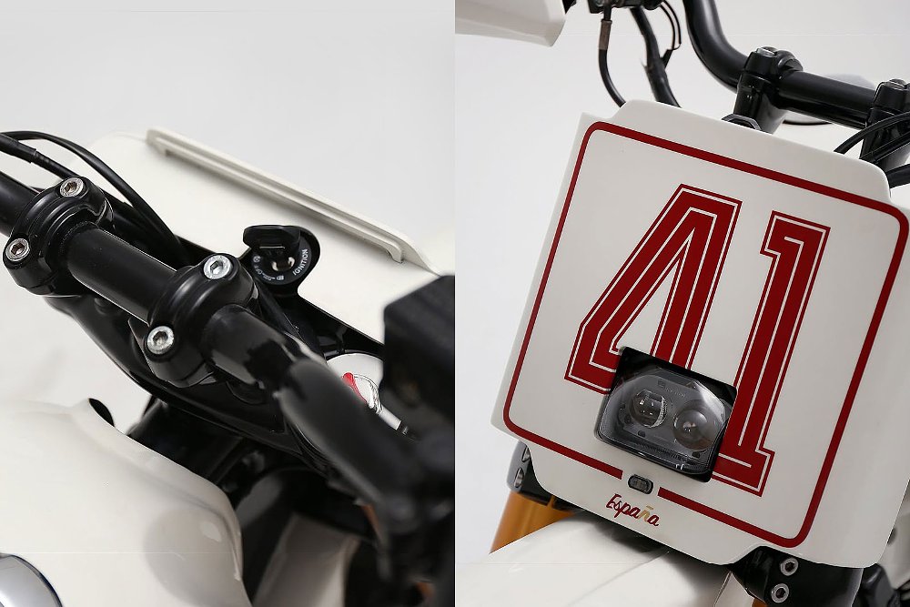view of the handlebar and front number plate with small, integrated lights