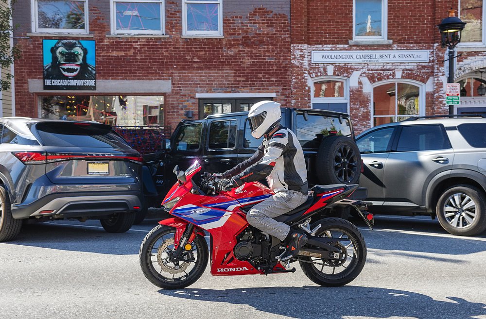 rider in town with parked cars along the storefronts