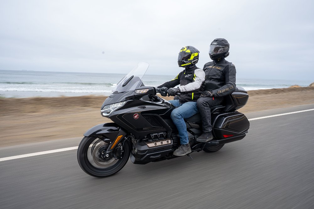Honda's Gold Wing Tour riding with rider and passenger with the ocean in the background.