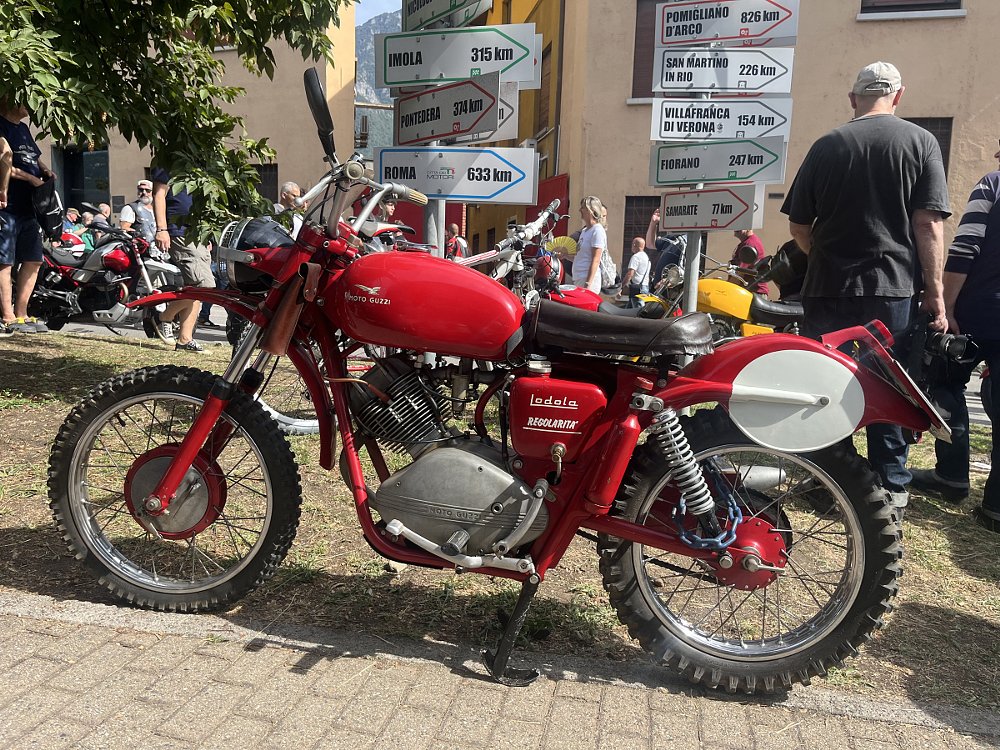 small red single-cylinder vintage Moto Guzzi parked on the street