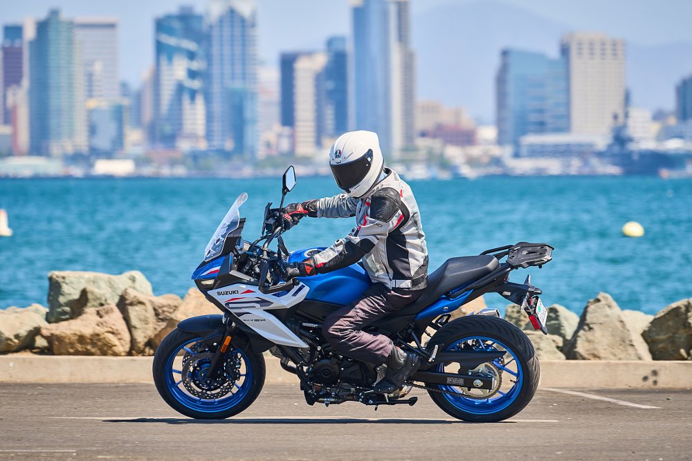 rider on the blue-and-white SV-7GX in front of the bay with the San Diego skyline in the distance