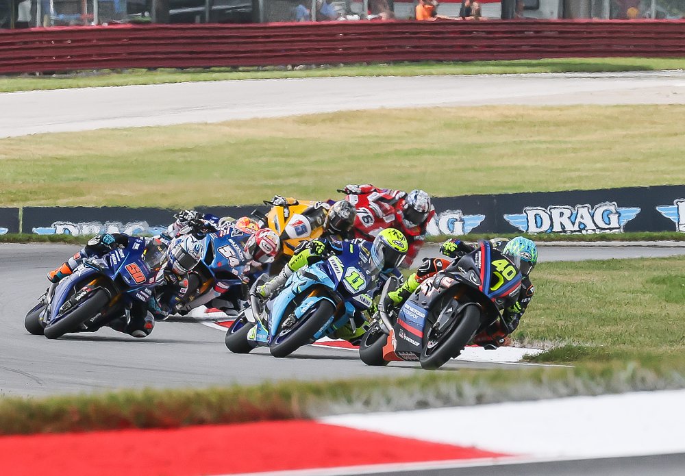 Kelly leads Scholtz and Fong and a pack of riders through a curve on the race track