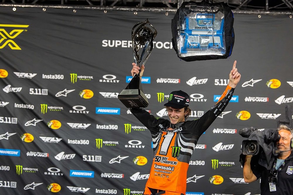 Levi Kitchen smiles and holds up a large silver trophy for winning the 250SMX title