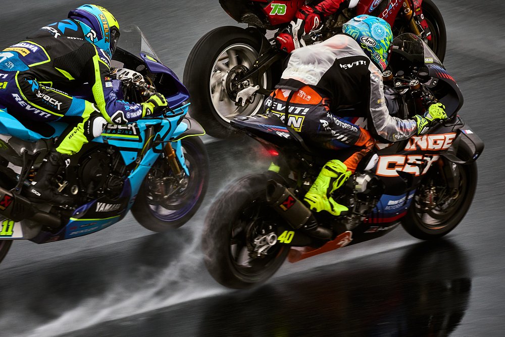 racers battle for position close together with water streaming off their rear tires