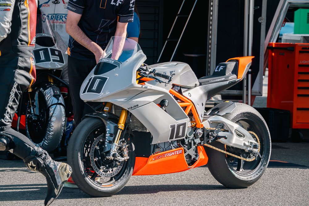 Lightfighter V3-RS parked in the paddock of Sonoma Raceway with people walking around.