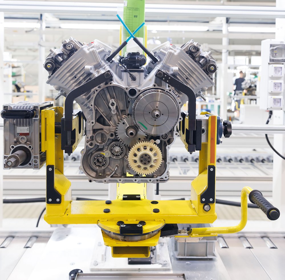engine on a yellow stand being assembled in the factory